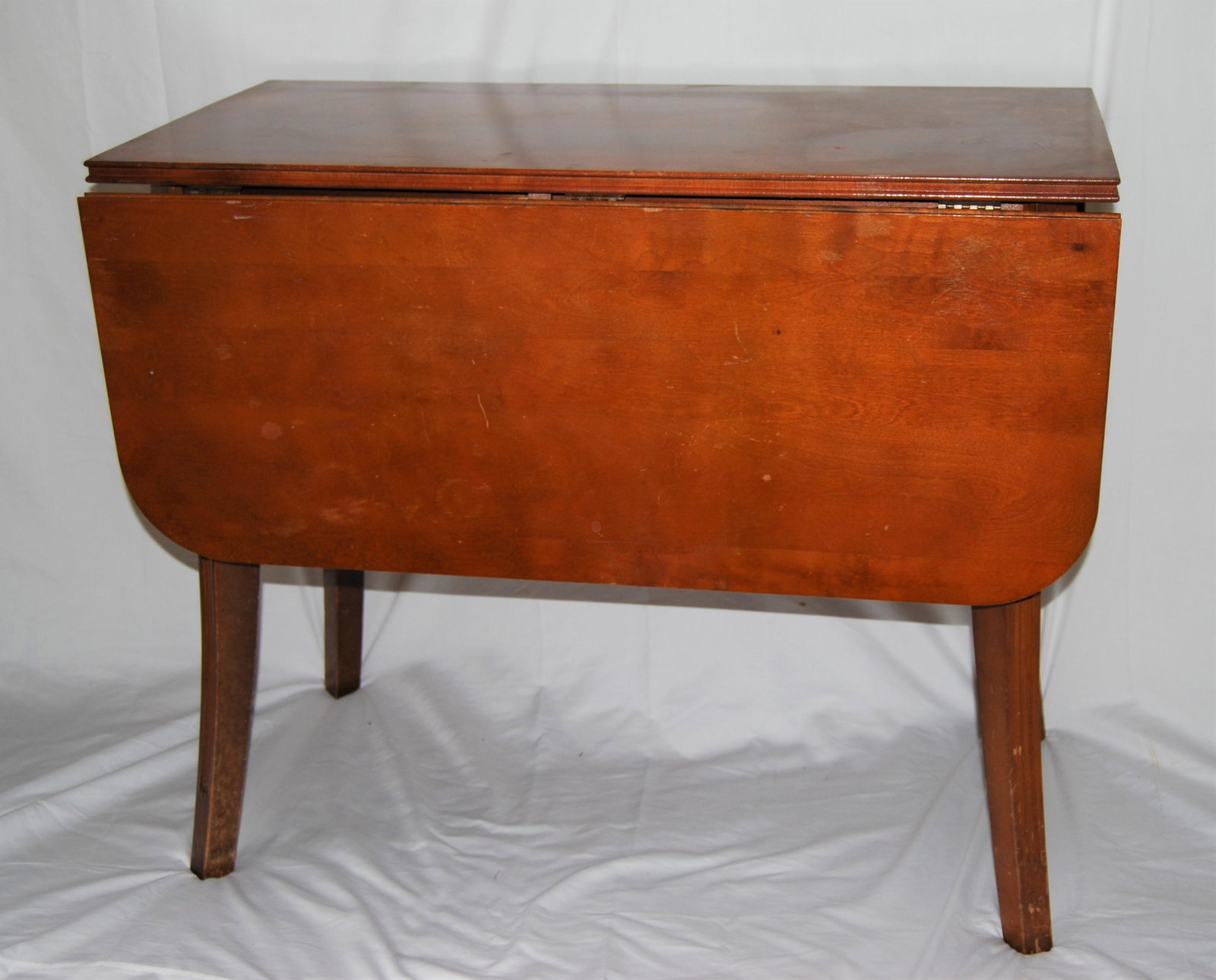 Vintage Pembroke Style Drop Leaf Maple Table: Vintage Pembroke Style Drop Leaf Maple Table. 1920’s table with two drop leaves and fluted saber legs. Shows wear appropriate to its age & use. 29”h x 35”w x 19”d. When top is 