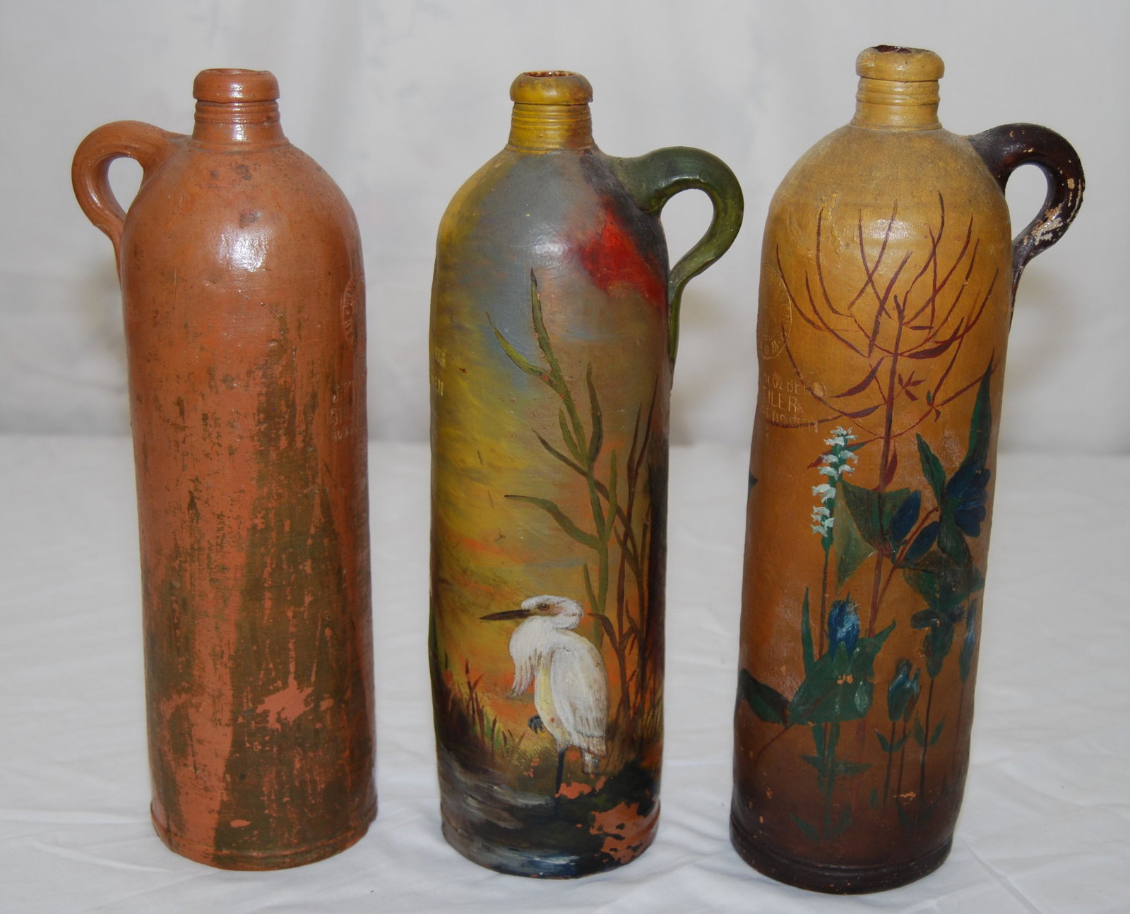 Salt-Glazed-Handpainted German Stoneware Bottles: Vintage 1800’s Salt-Glazed German Stoneware Bottles. Lot of 3 items includes: two hand painted beer bottles with woodland scenes (one has a stork), both are by and marked ”Georg Kreuzberg 