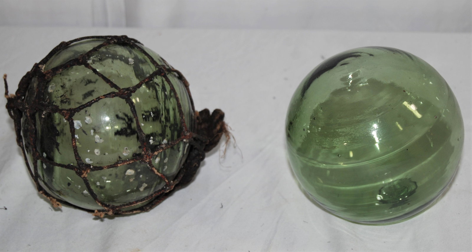 Antique Blown Green Glass Fishing Floats: Two - Antique New England or Maritime Canadian Green Blown Glass Fishing Floats. Used for either fishing nets or sometimes as lobster trap floats. No seams, blown glass, with pontil, there is a propel