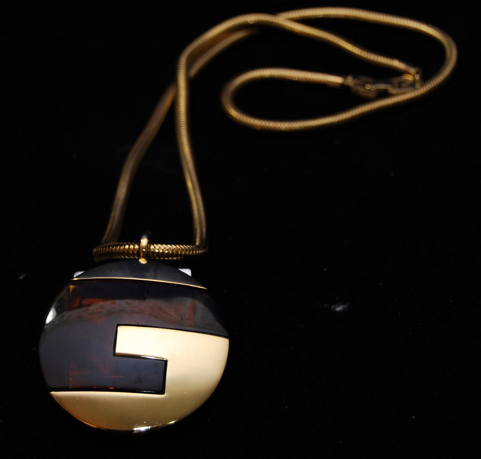 Givenchy Gold Plated 1977 Pendant with “G”: Givenchy Gold Plated Pendant. Modernist pendant with the gold and tortoise shell “G” logo monogram, snake chain, “G” logo clasp. It is marked “GIVENCHY Paris New York 1977”. Pendant is 1 7