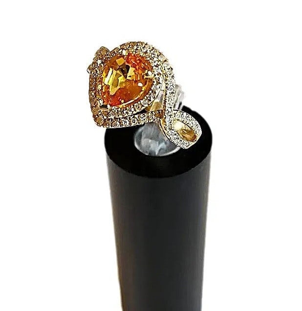 14K Gold Setting Featuring a 2+ct Pear Shaped Orange Sapphire surrounded by Diamond Chips. Size 6: This is one of our nicer pieces. Large, pear-shaped Orange Sapphire - 2+ ct center stone set in a 14k yellow gold setting with swirls of tiny diamond chips. This ring is new. Size 6 1/2. Can be re-siz