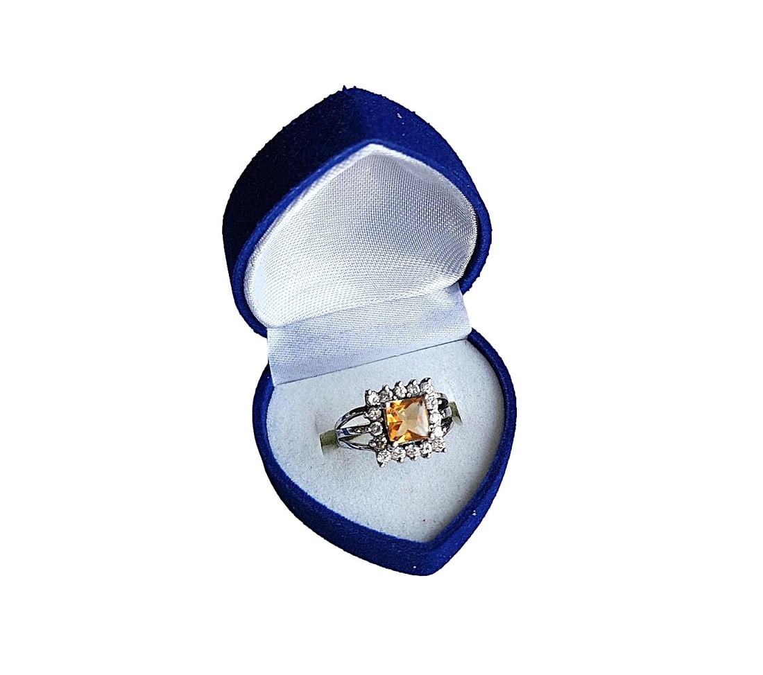 Square Cut Genuine Citrine ring surrounded by CZ stones in Sterling Silver setting. Size - 7: Very nice square cut Citrine center stone with deep color. The stones surrounding the Citrine test as Cubic Zirconia. The setting is stamped 925 - Sterling Silver. The ring is Size 7. It can be re-siz