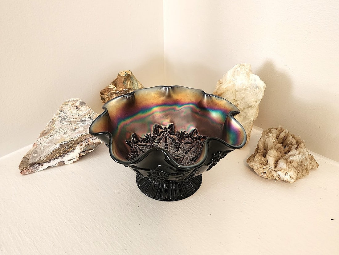 Black Carnival Glass Bowl w/ Fluted Top: Nicely colored Carnival glass piece. Features a fluted top and short pedestal foot. Maker Unknow. Measures: 7" wide x 4" tall.