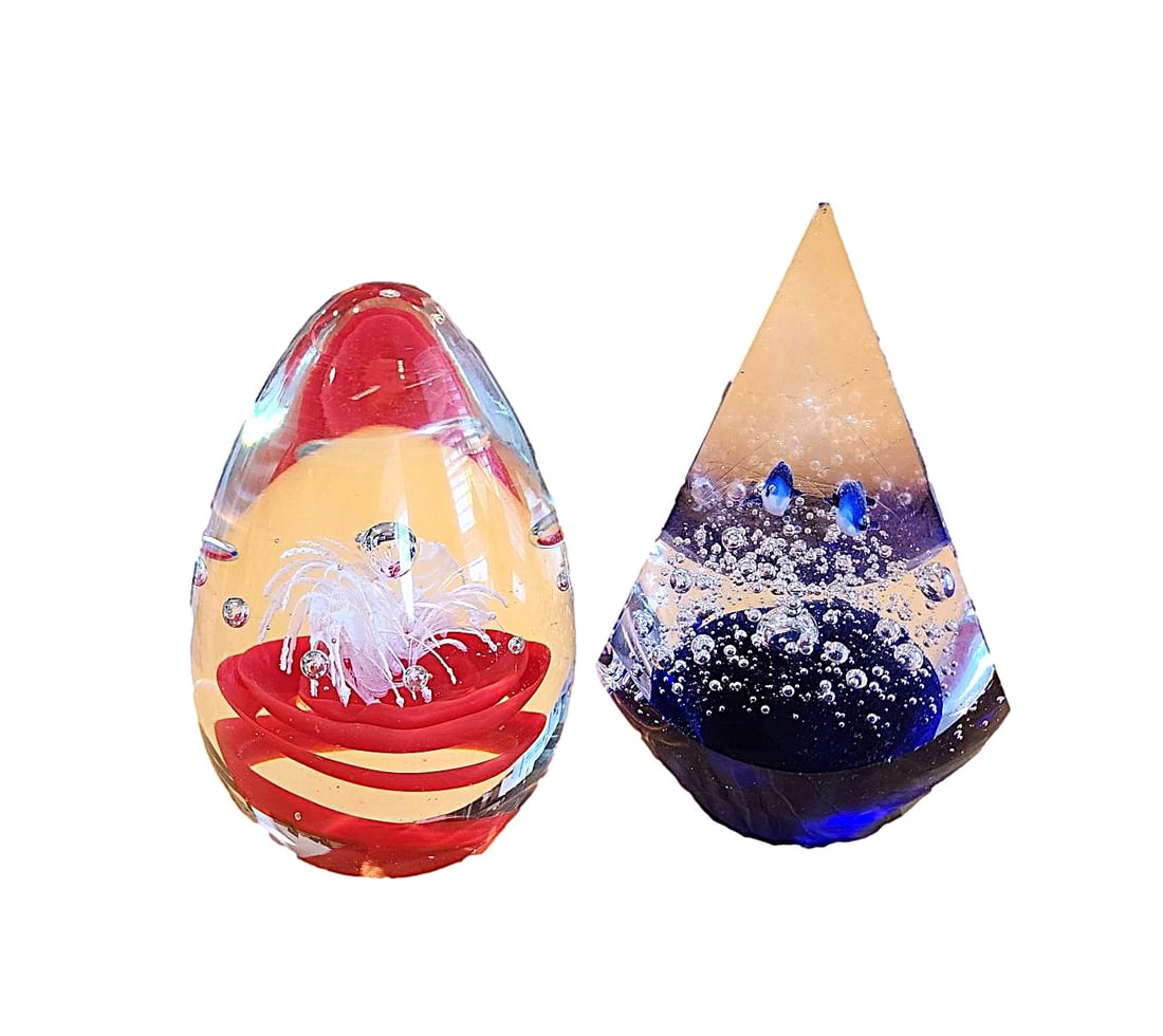2 Paperweights - One featuring a Bubble with Spray and one a Sea Scene: These 2 paperweights are unmarked. One features a red base with white spray and center bubble. The other features fish in an underwater scene. The fish weight has a sliver chip on the top point. 5" ta