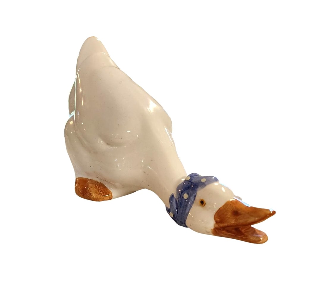 Vintage Downward crouching ceramic duck/goose figurine: Unknown Maker. This adorable duck (could be a goose) is crouching down in a playful manner and wearing a blue and white spotted scarf. Measurements: approx 11 x 7 x 5.