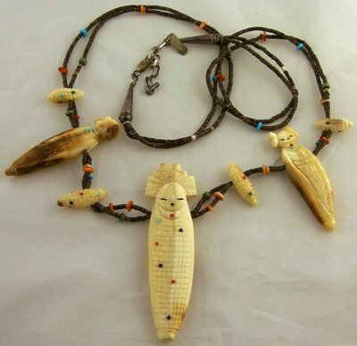 Cornmaiden fetsih necklace: Contemporary hand carved 'corn maiden' fetish necklace comprising 3 fossilised ivory corn maidens & 4 corn cobs set on an olive shell necklace, 700mm long, largest fetish 80mm high; other 2, 55mm high