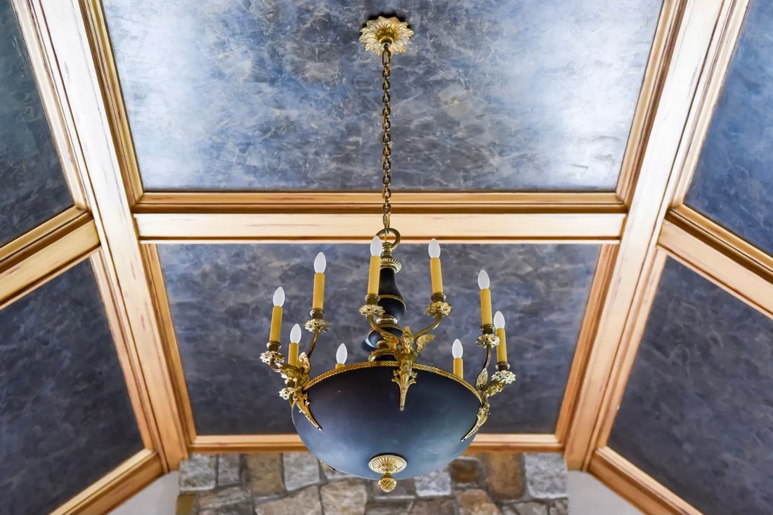 Empire Style Gilt Bronze Winged Ten Light Chandelier: Ten light Empire style black and bronze chandelier with winged female figures, pineapple detail at base. Purchased for $6,800 at Nicholas Antiques, D&D Building, NYC. Dimensions: 25" Diam. x 32" H (no