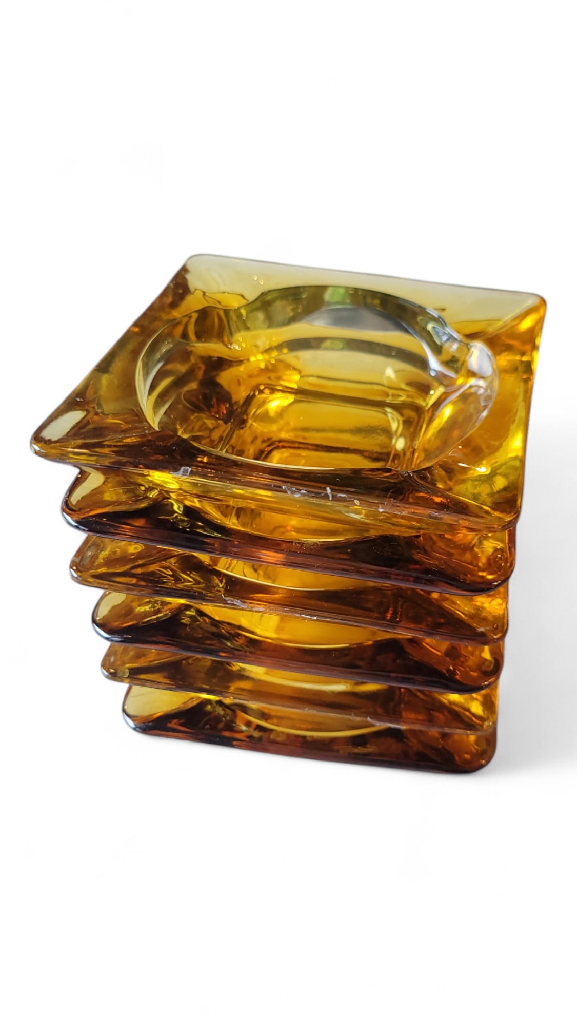 Vintage Set of 6 Amberina Ashtrays: Offered is a vintage set of six amber glass ashtrays, each showcasing the warm, honeyed tones and clean lines characteristic of mid-century modern design. These pieces reflect both function and style,