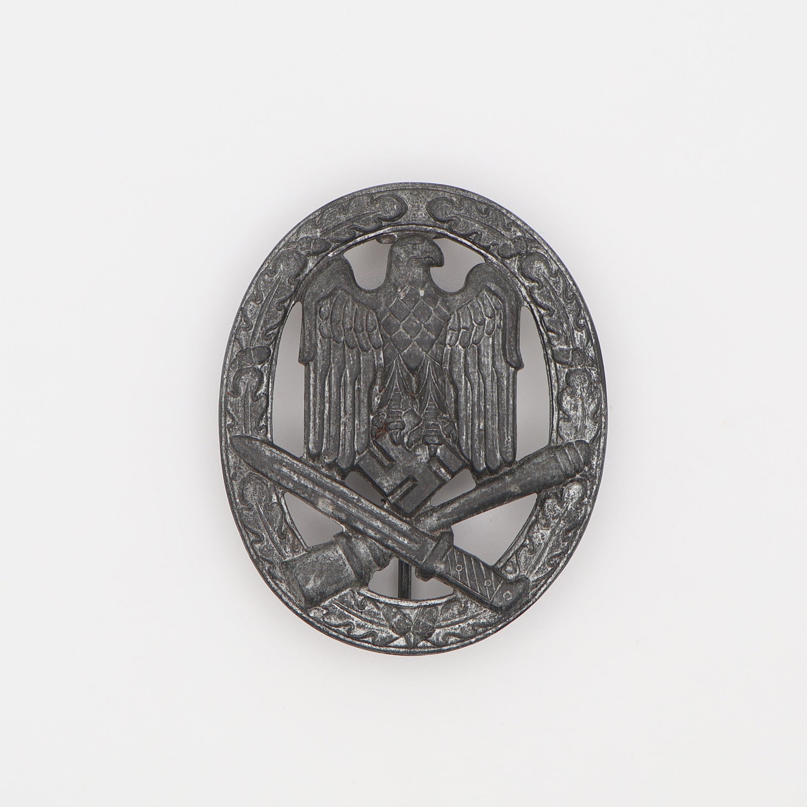 German WWII General Assault Badge: German, Third Reich (c. 1939-1945). General Assault Badge (Allgemeines Sturmabzeichen), in silvered zinc, an oval oak-leaf wreath enclosing an eagle grasping a mobile swastika above a crossed bayonet 