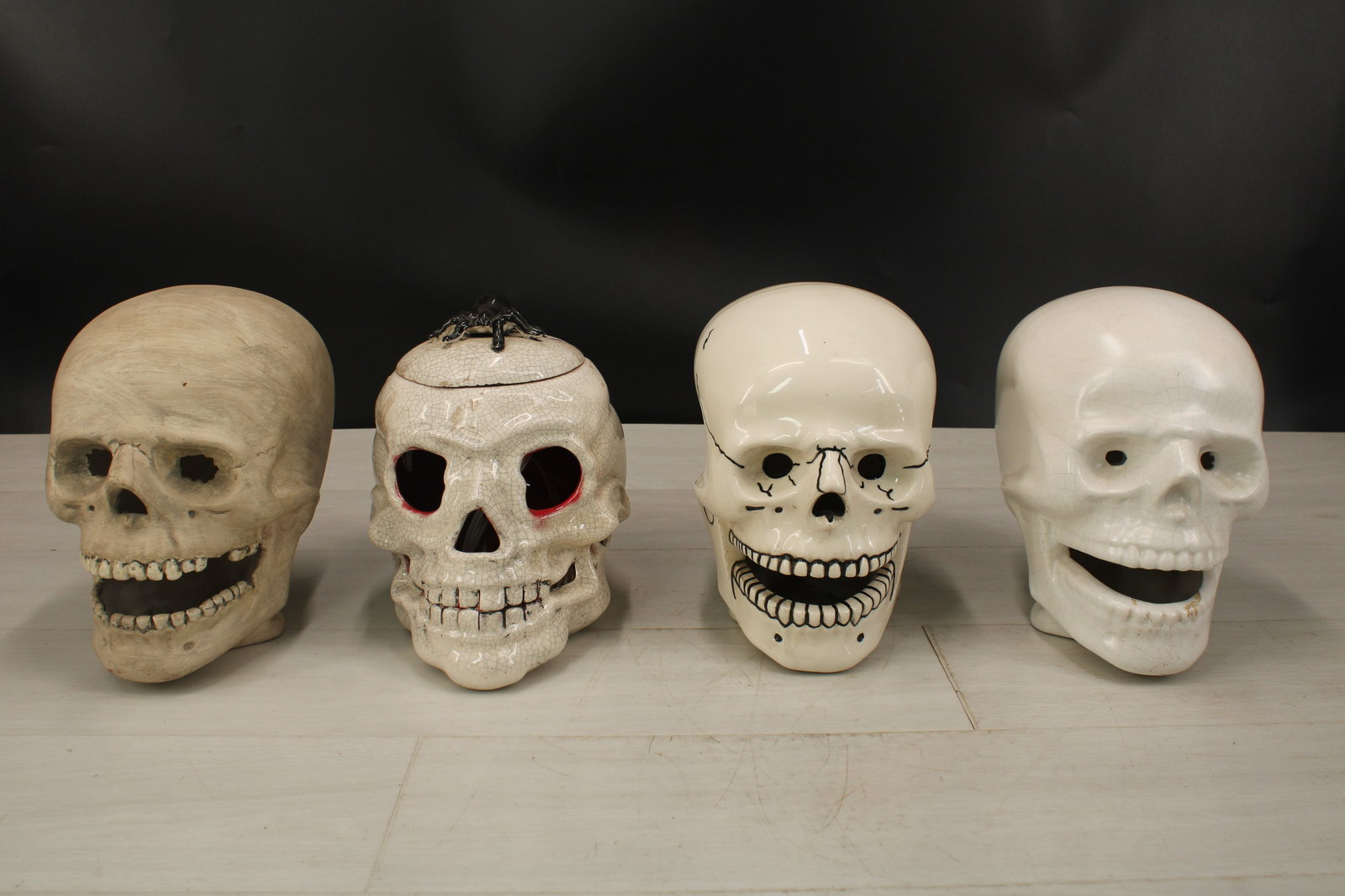 4 ceramic skulls, one with spider, lid, and hole at the bottom. Size: largest 8.5" H x 6" W x 9" D: 4 ceramic skulls, one with spider, lid, and hole at the bottom. Size: largest 8.5" H x 6" W x 9" D