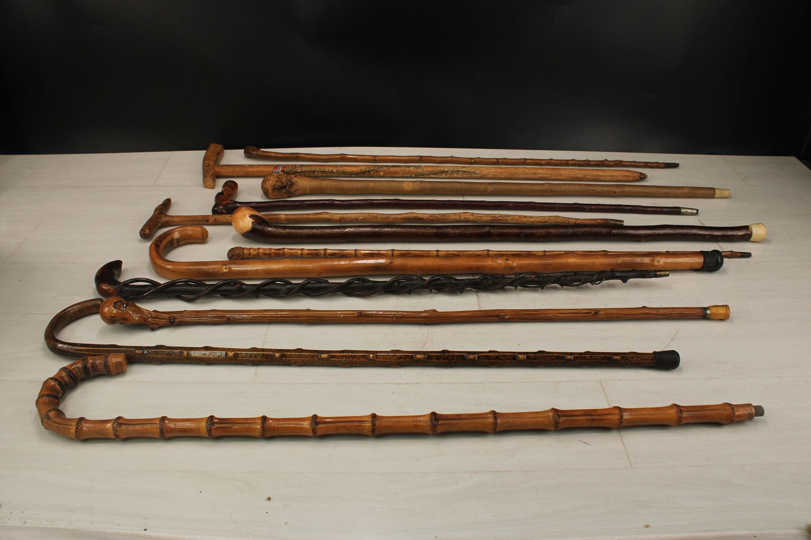 Group of VTG and Antique Wooden Walking Sticks: A collection of twelve wood canes/walking sticks including bamboo, twig, and painted all with a variety of handles. Size: 35"longest