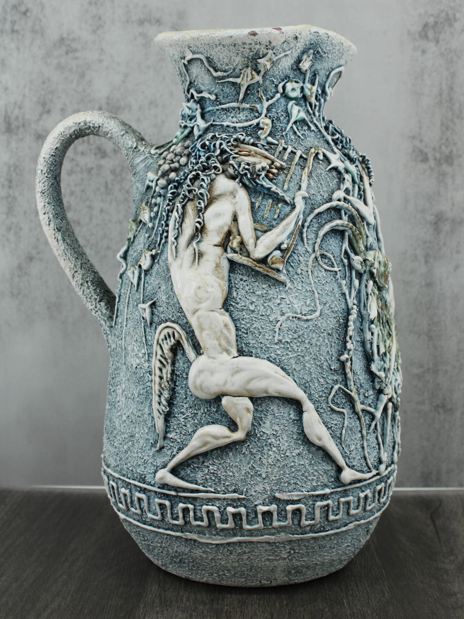Neoclassical Centaur Ceramic Pitcher: Hand thrown studio pottery pitcher, likely mid century. Has an all over applied neoclassical motif, 2 nude male centaur figures and a nude female on a goat seemingly telling the story of the kidnappin