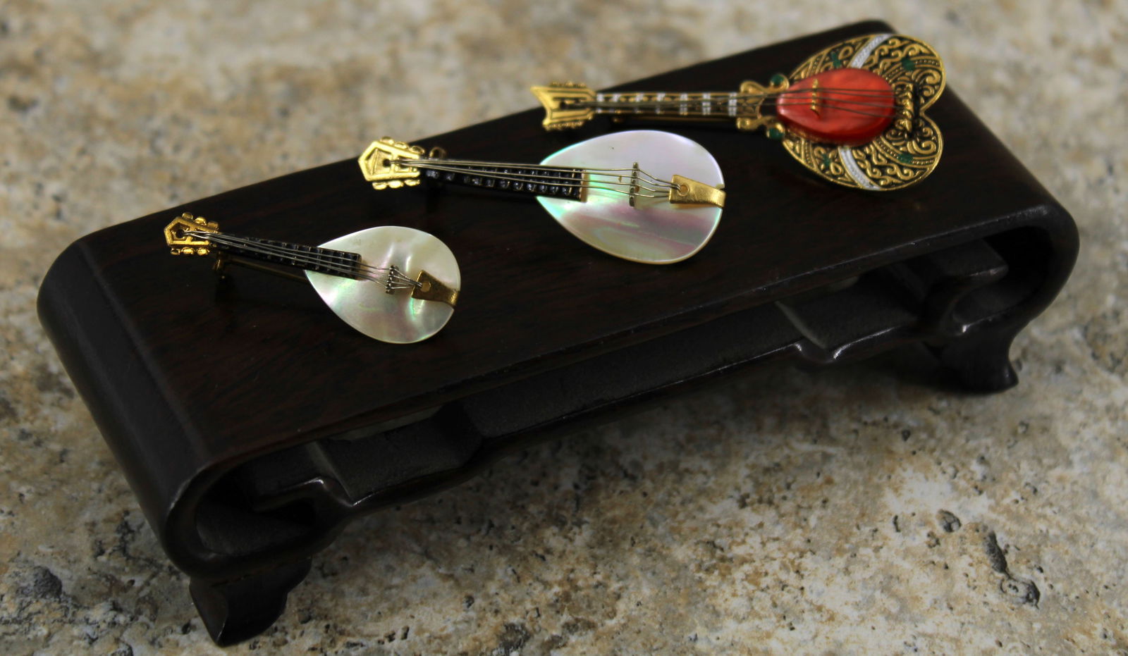 Vintage Mandolin Theme Brooches: Three mandolin shaped pins made of mother of pearl, brass, glass, and enamel. The largest pin, with pink glass, is marked Spain. Middle size has no markings and the smallest is marked Made in West Ger