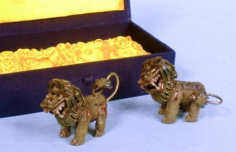 Pair of Chinese Silver & Enamel Foo Dogs: A matched pair of Chinese silver foo dogs decorated with cloisons of green, purple, blue and white enamel. In original 3 1/2" x 6 1/2" satin-lined box, each foo dog measures 2"h x 3"w.