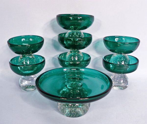 Pairpoint Art Glass Eight Piece Controlled-Bubble Compo: An Erickson Pairpoint hand blown eight piece comport set, of deep emerald green crystal with clear controlled bubble-ball stems. Includes one 8 1/2"w x 4 1/2h" centerpiece and seven matching 5"w x 4 1