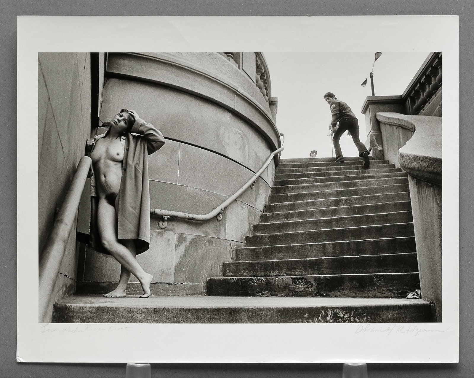 Signed by both Diane Schmidt and Michele Fitzsimmons - Lower Wacker Riverfront 12"x7.5" Photograph: Scarce and compelling, this vintage gelatin silver photograph from Diane Schmidt’s The Chicago Exhibition (1979–1984) captures Michele Fitzsimmons nude in a daring urban context. A striking opport