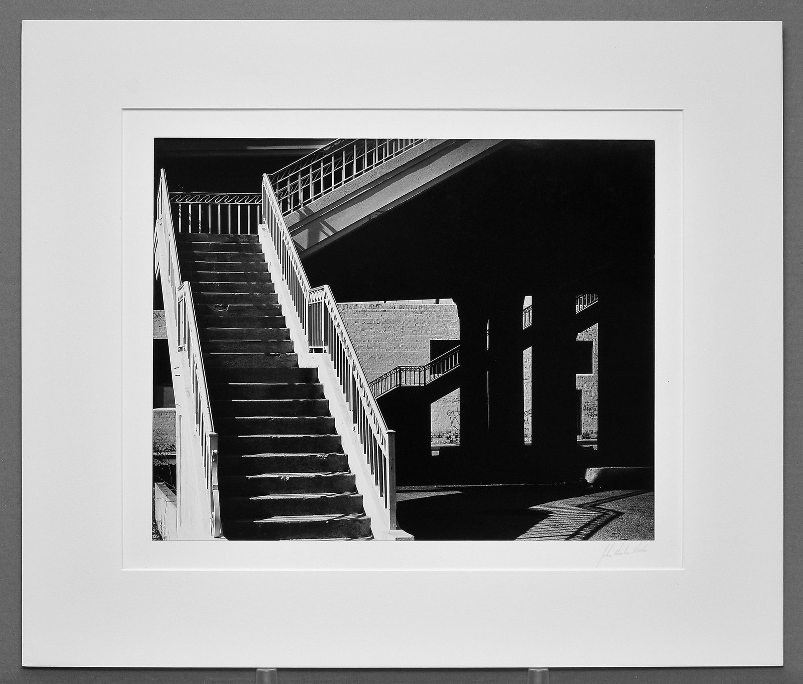 John Charles Woods (1952 -) Los Angeles, 1979 Photograph 15"x18.5" - Rare!: A powerful early architectural study by John Woods, echoing the bold graphic vision of Brett Weston{index=0}> through light, shadow, and form. Los Angeles (1979, printed 1980) transforms a simple urba