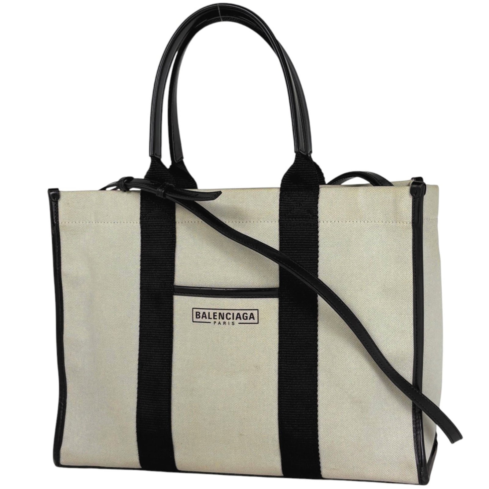 Canvas and leather Balenciaga tote bag: Canvas and leather Balenciaga tote bag A timeless Balenciaga tote bag, crafted from durable canvas and supple leather, boasts a sleek black finish with subtle white accents. Its spacious interior and