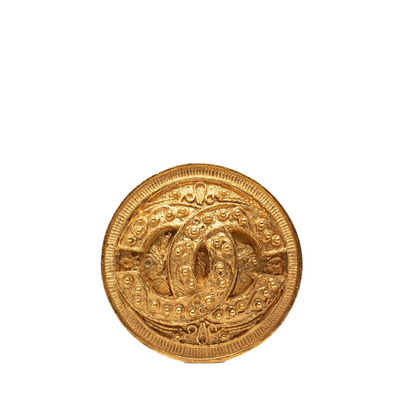 Brooch Chanel: Brooch Chanel A stunning Chanel brooch, crafted in 18k gold, adds a touch of timeless elegance to any outfit. With its classic design and subtle scratches from years of wear, this pre-owned piece