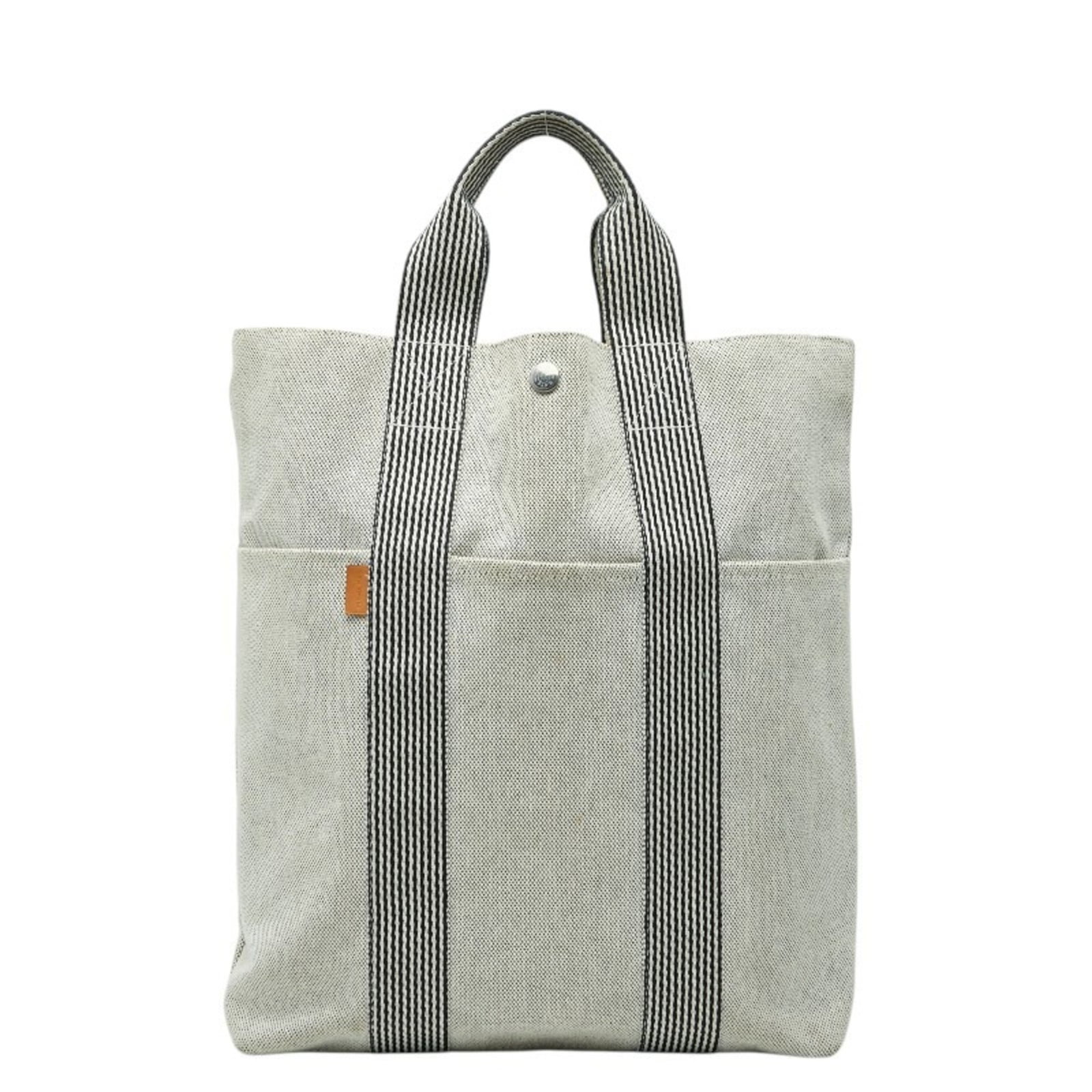 Hermes Canvas Tote Bag: Hermes Canvas Tote Bag A pre-owned Hermes canvas tote bag in a beautiful gray hue, perfect for everyday errands and travel. With its classic design and durable canvas material, this timeless piece is