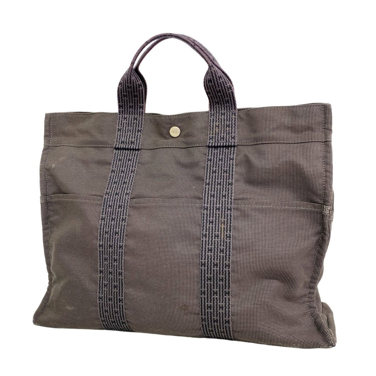 Hermes Canvas Tote Bag: Hermes Canvas Tote Bag A pre-owned Hermes canvas tote bag in timeless gray, boasting classic silver hardware and a sturdy canvas construction that exudes understated elegance. With its spacious interi