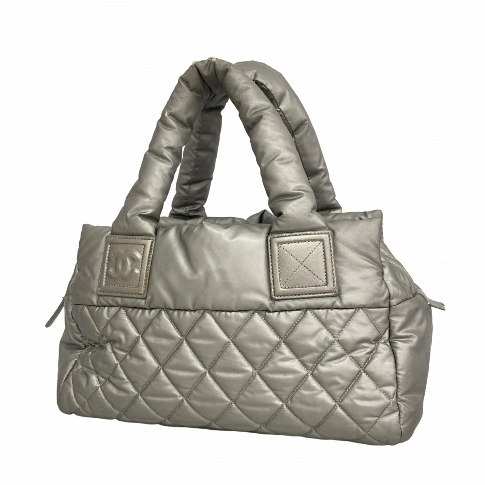 Chanel Tote Bag in Nylon: Chanel Tote Bag in Nylon A sleek and timeless Chanel tote bag in silver nylon, perfect for everyday use, boasts the iconic interlocking CC logo on its sturdy hardware. With its classic design and dura