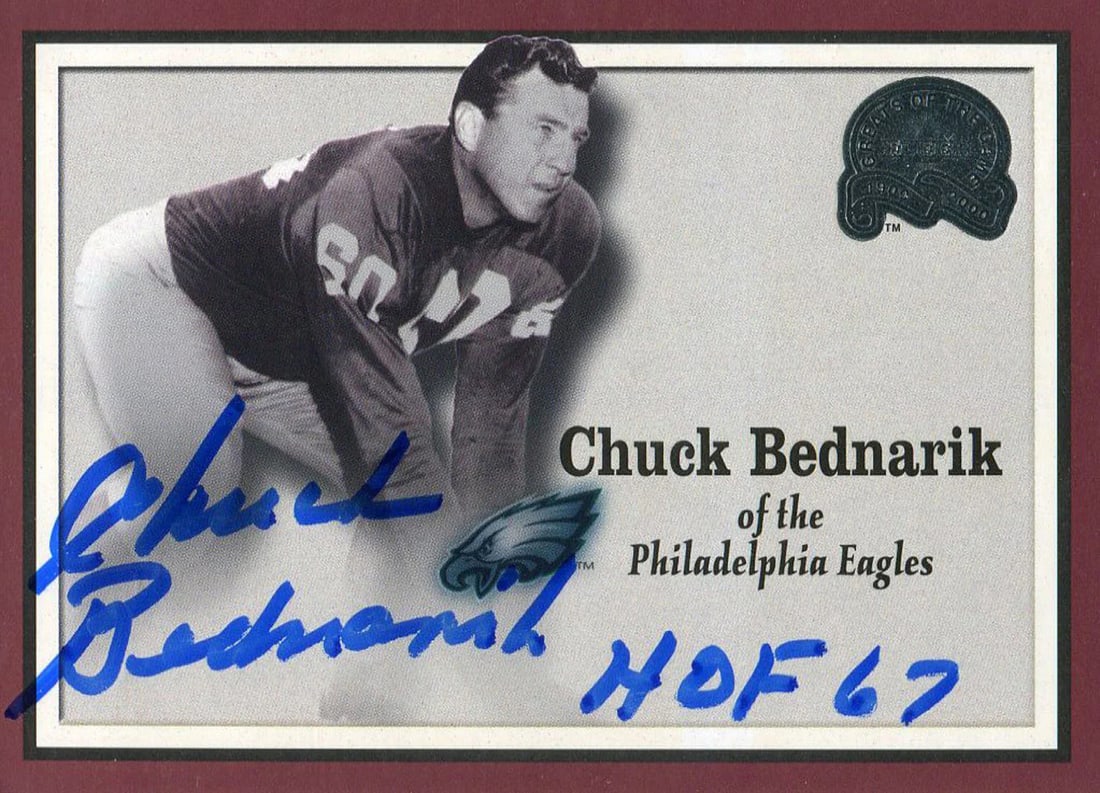 Chuck Bednarik '67 HOF Autographed 2000 Fleer Card: Chuck Bednarik '67 HOF Autographed 2000 Fleer Card Meet the legendary Chuck Bednarik, a two-time NFL champion and Hall of Famer, who has signed this 2000 Fleer card in blue pen across the front. Authe