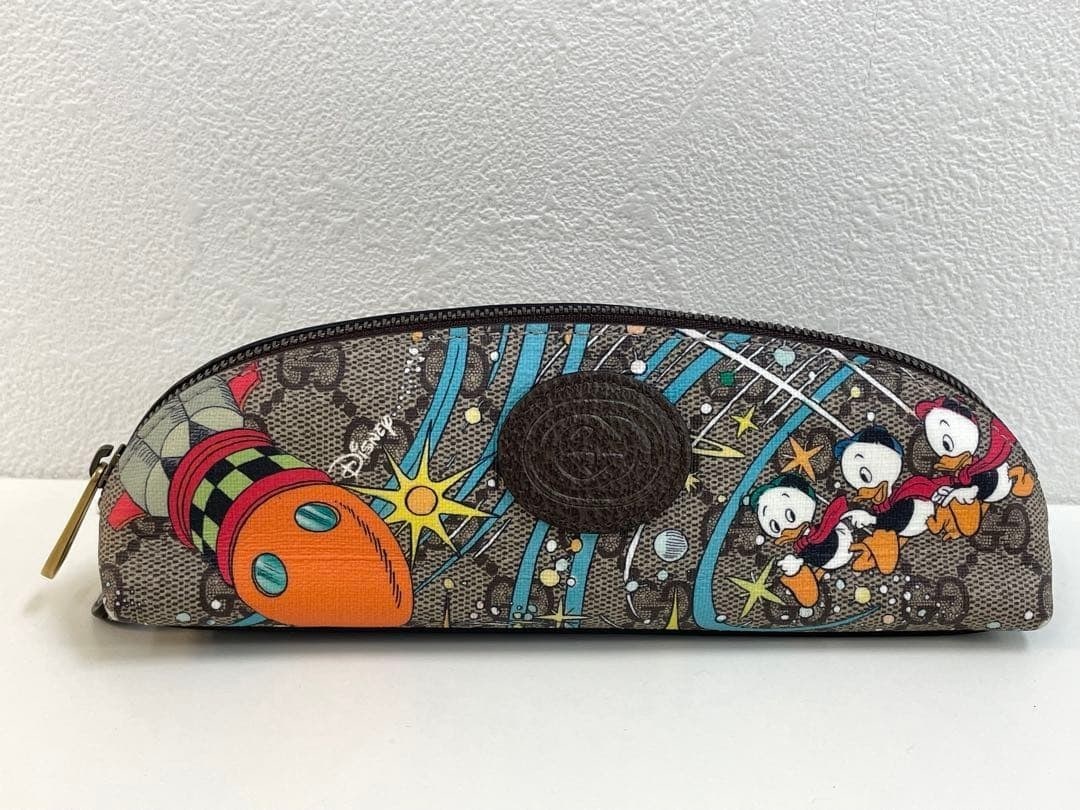 Gucci Disney Donald Duck Pen & Pencil Case with GG Pattern Zipper: Gucci Disney Donald Duck Pen & Pencil Case with GG Pattern Zipper Elevate your everyday essentials with the Gucci Disney Donald Duck Pen & Pencil Case, showcasing the iconic GG pattern and vibrant mul