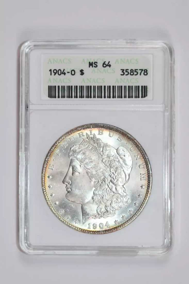 LOOKS NICER VERY PQ SOAPBOX - 1904-O MORGAN DOLLAR ANACS MS64: LOOKS NICER VERY PQ SOAPBOX - 1904-O MORGAN DOLLAR ANACS MS64 A rare and highly sought-after 1904-O Morgan dollar, graded MS64 by the esteemed ANACS organization, is up for auction. This uncirculated