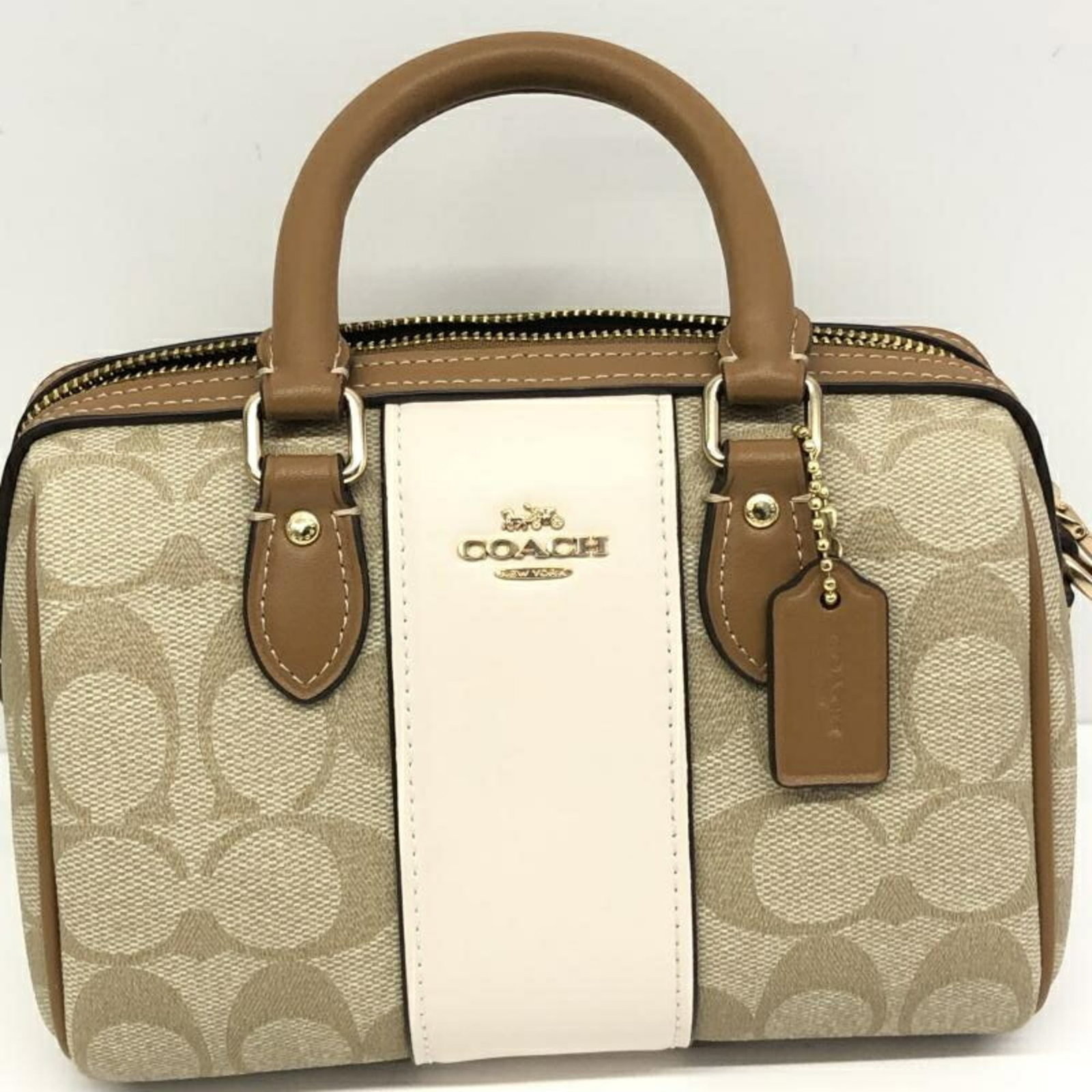 Signature line handbag by Coach: Signature line handbag by Coach Elevate your everyday style with this stunning Coach handbag, crafted from the iconic Signature Line. Its classic beige hue and sleek design make it a timeless