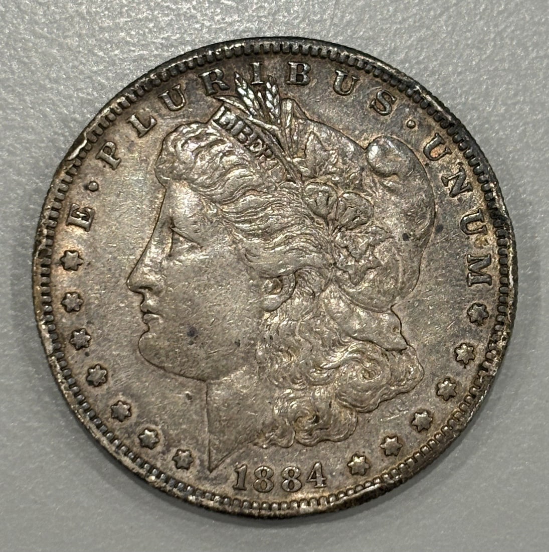 1884-S MORGAN DOLLAR AU: 1884-S MORGAN DOLLAR AU A rare find for the collector, this 1884-S Morgan dollar is a stunning example of American numismatics, boasting its original silver content and circulated condition.