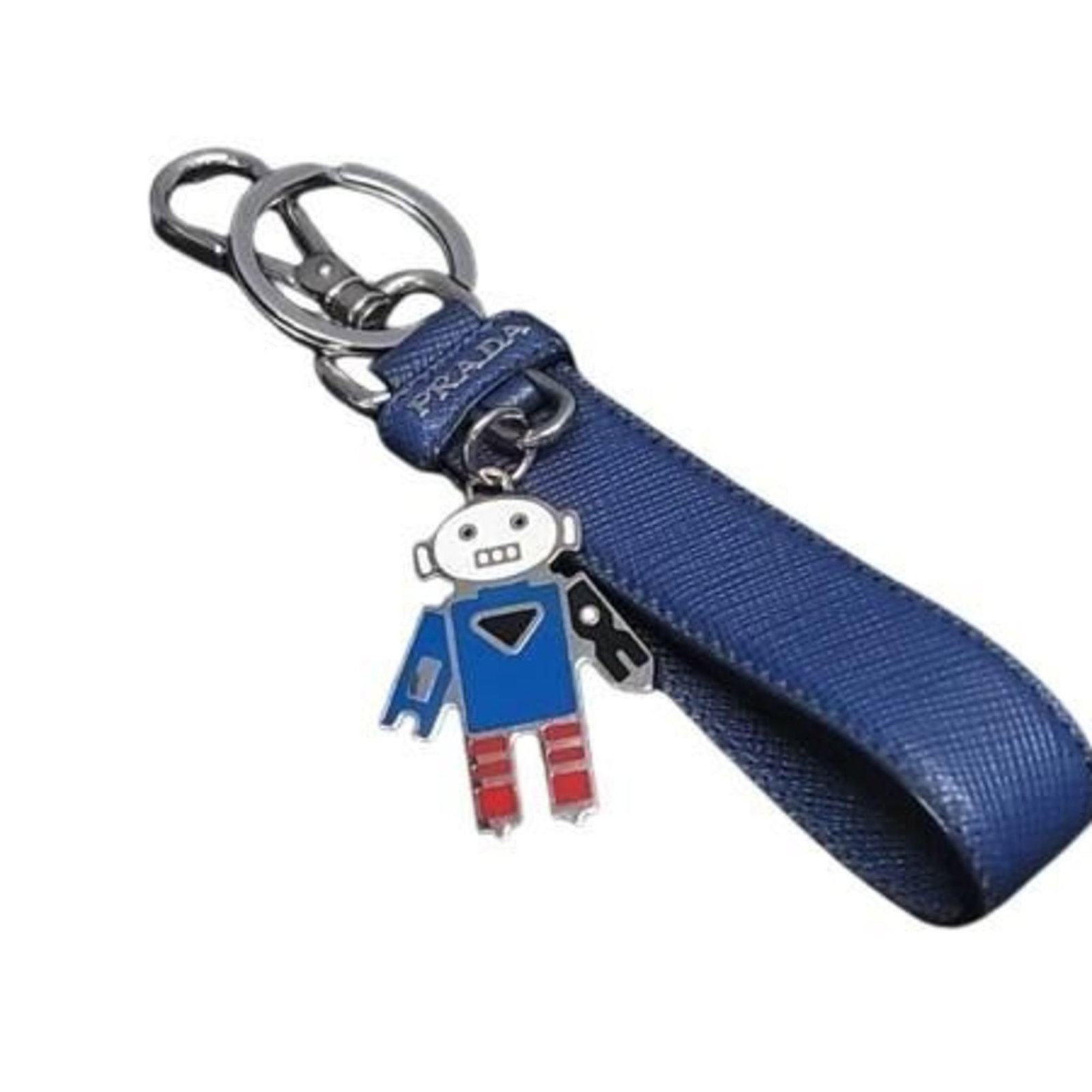 Prada Handbag Leather Charm: Prada Handbag Leather Charm A unique Prada leather charm adorns this handbag accessory in a striking blue hue. Made from genuine leather, the charm showcases subtle signs of wear and tear, adding to