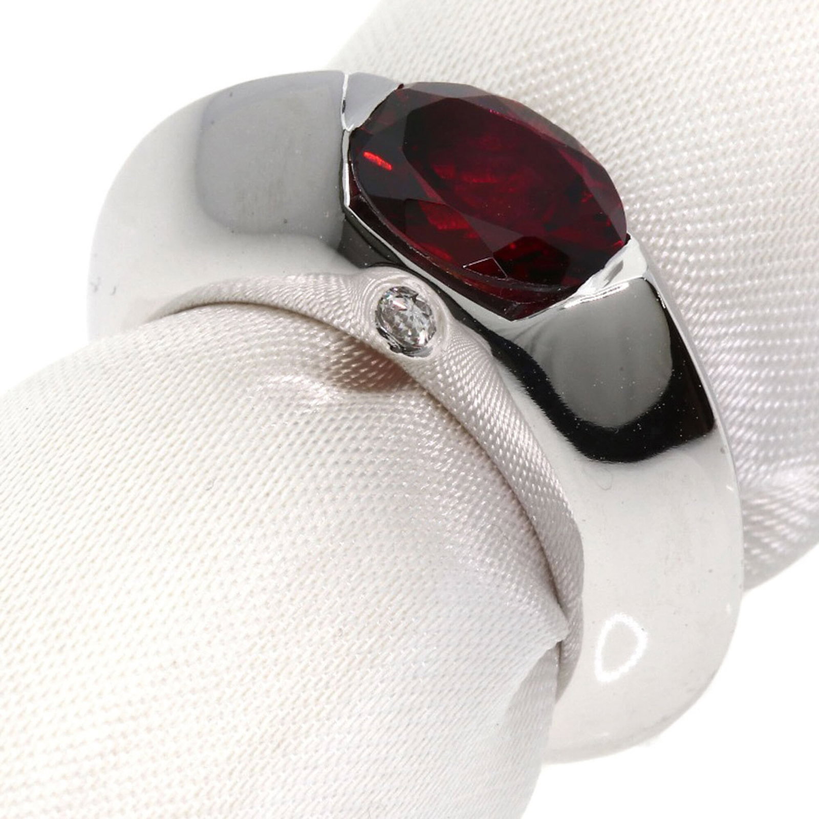 Piaget Band Ring White Gold (18K): Piaget Band Ring White Gold (18K) Piaget Band Ring White Gold (18K) features a diamond and garnet stone set in 18K white gold. The ring's used condition shows some traces of usage with minor scratches