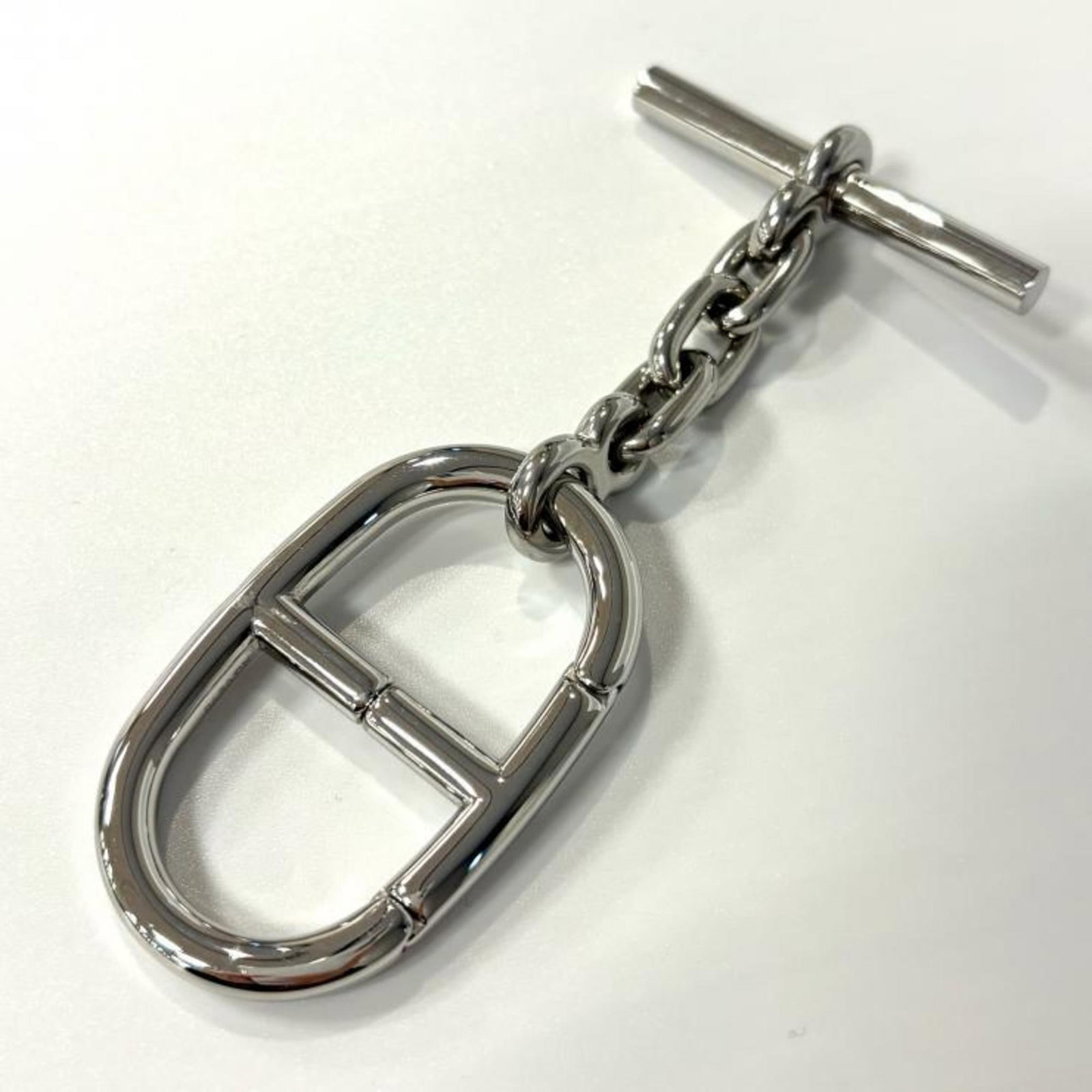 Hermes Handbag Charm Rhodium: Hermes Handbag Charm Rhodium Rhodium-plated charm from iconic luxury brand Hermes, bearing subtle signs of previous use. The small size and delicate design make it a versatile accessory for handbags