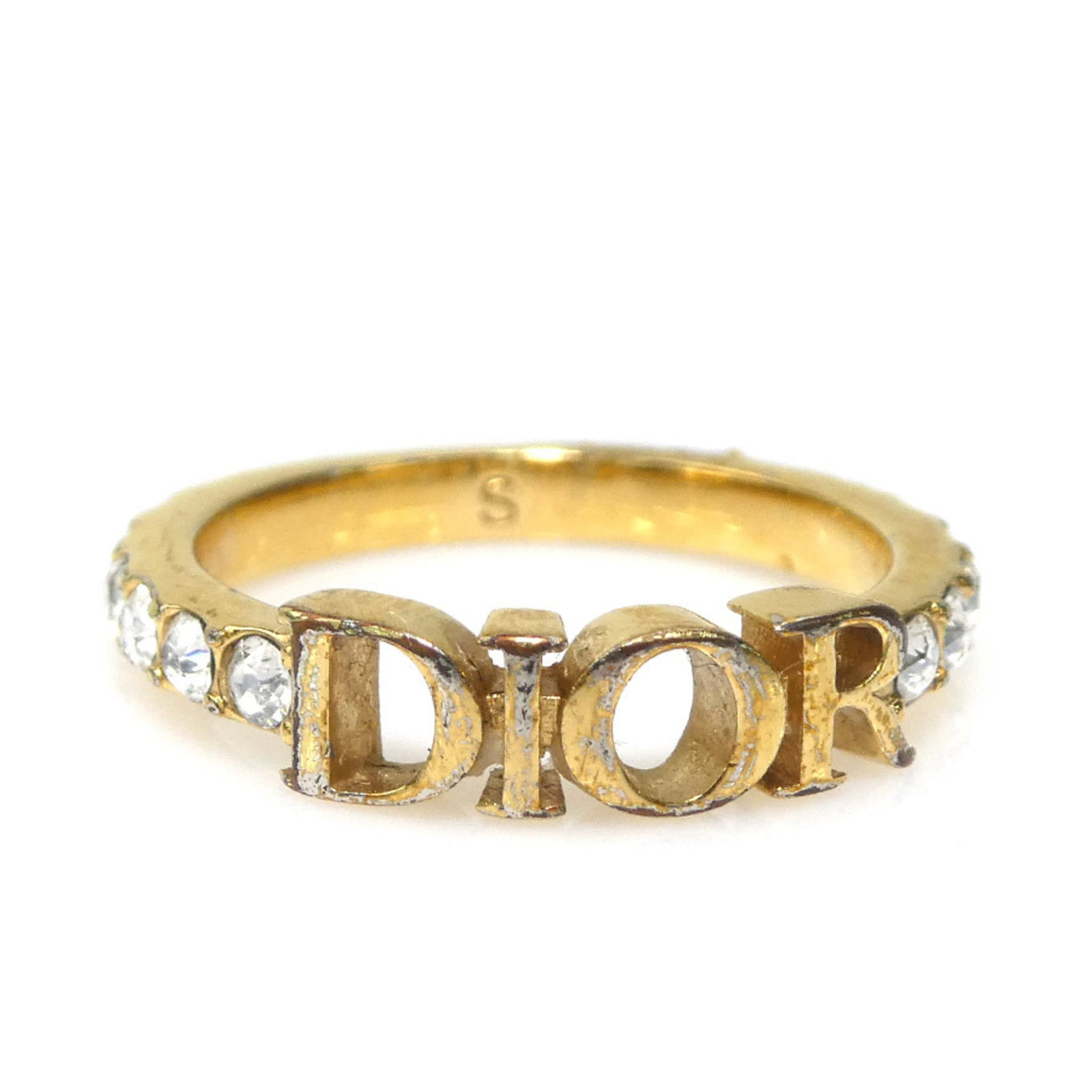 Christian Dior Band Ring Metal, Rhinestone: Christian Dior Band Ring Metal, Rhinestone Gold band ring from Christian Dior features metal and rhinestone design. The piece shows signs of use with traces of scratches and dirt, indicating its used 