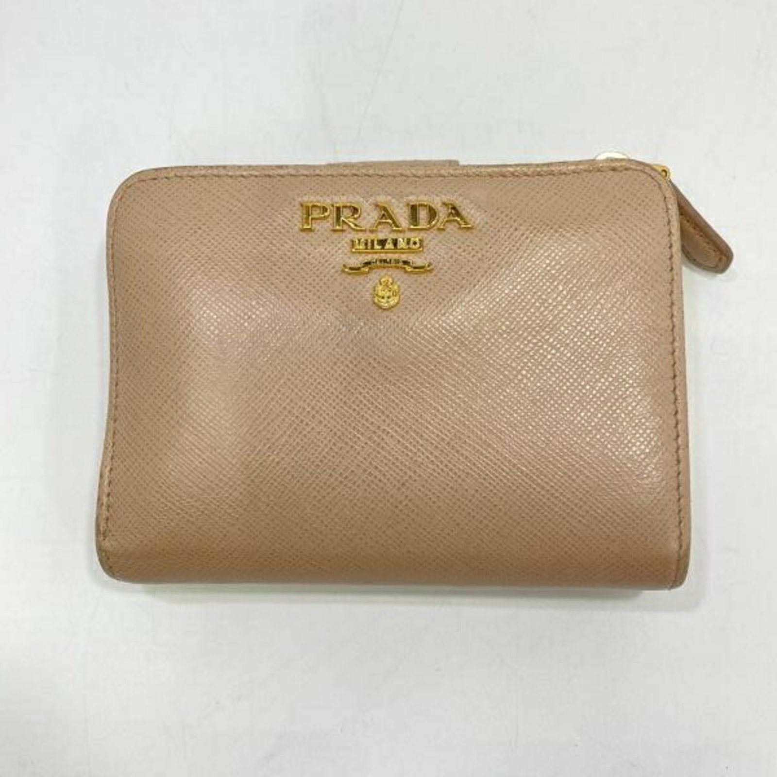 Prada Wallet (Bi-Fold): Prada Wallet (Bi-Fold) This Prada bi-fold wallet features a classic design with clean lines and a timeless beige color. With its compact size and durable construction, it remains a practical and styli