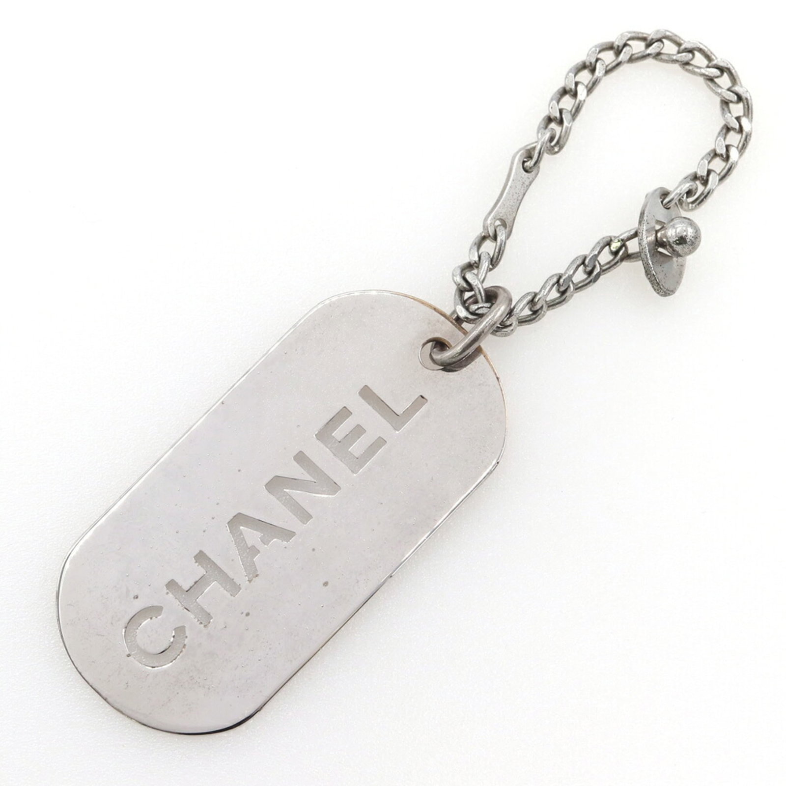 Chanel Keyring Metal: Chanel Keyring Metal This silver Chanel keyring features a sleek metal design. Traces of usage are visible, with minor scratches and dirt, but overall in good condition. A subtle touch of luxury from 