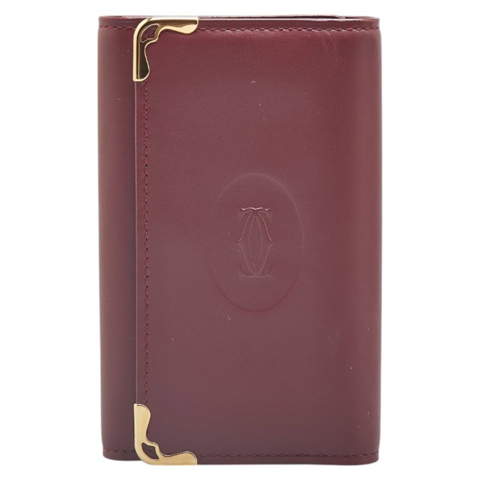 Cartier Keycase Leather: Cartier Keycase Leather Wine Red Cartier Keycase Leather - A stylish and sophisticated accessory in very good condition. The leather shows some traces of usage with minor scratches and dirt, adding to