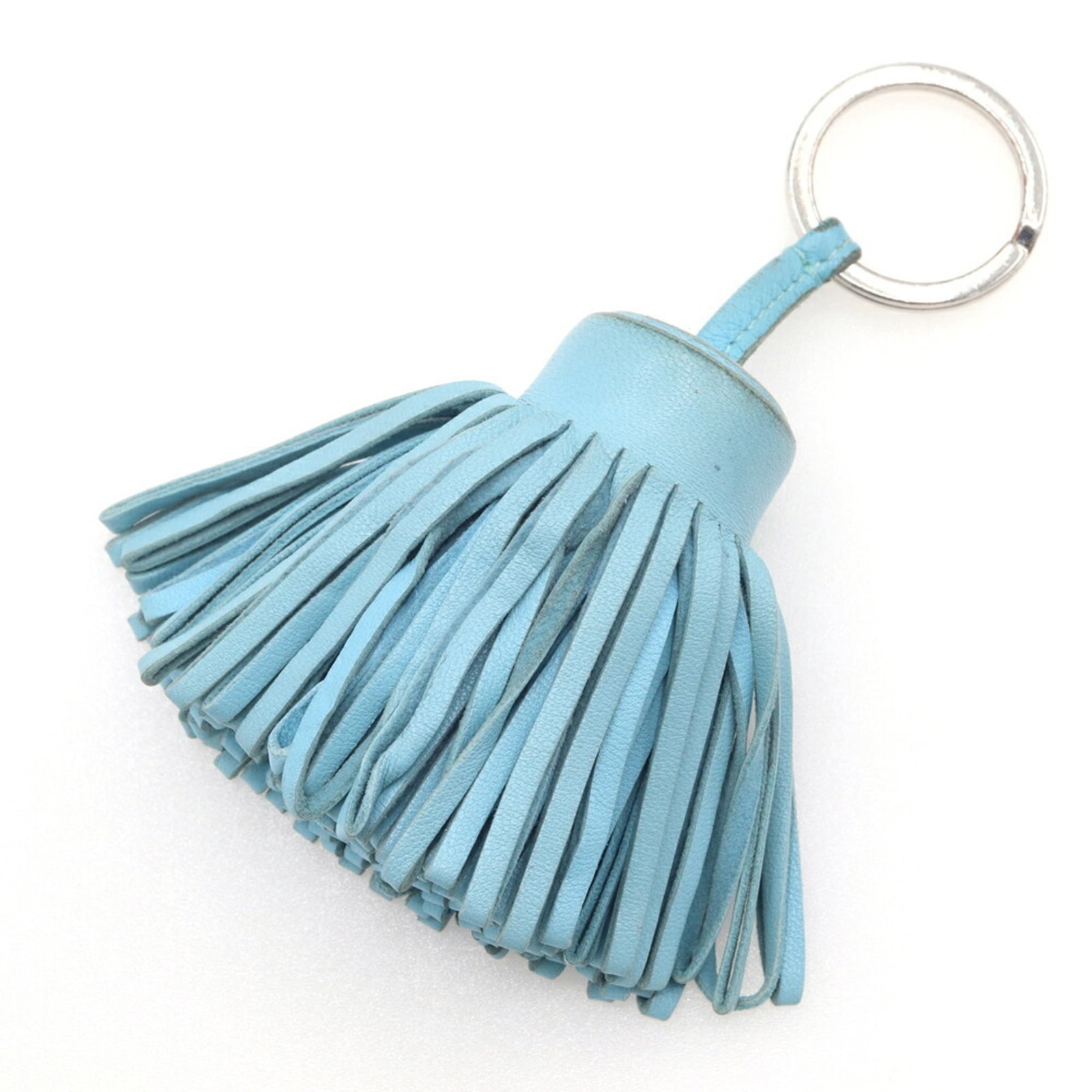 Hermes Keyring Agneau Milo: Hermes Keyring Agneau Milo Agneau Milo keyring from Hermes features a light blue hue. The material has some traces of usage and minor scratches, indicating general wear. Overall, its condition remains