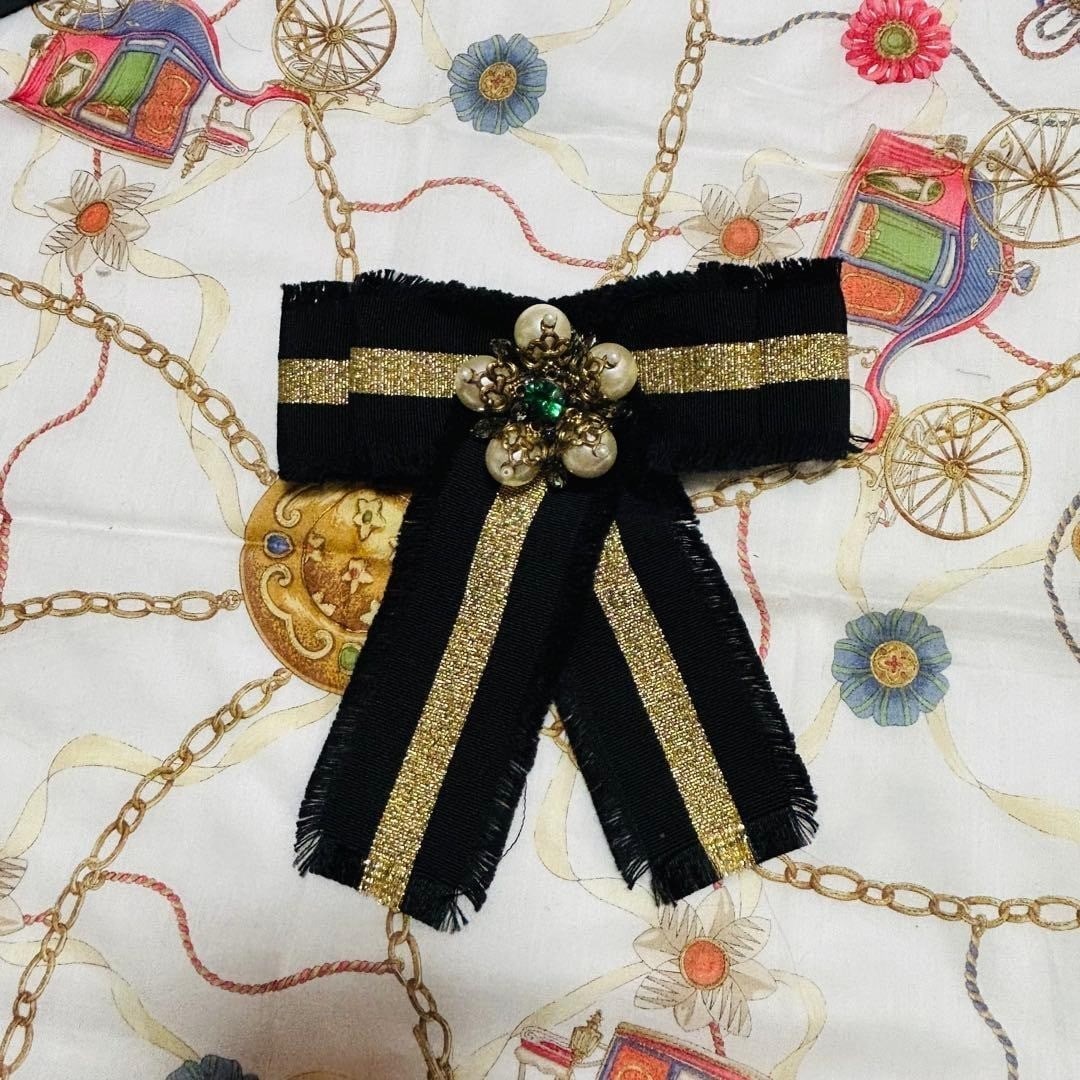Gold and Black Ribbon Pin Brooch in Faux Pearl with Original Box: Gold and Black Ribbon Pin Brooch in Faux Pearl with Original Box Gold and black ribbon pin brooch in faux pearl with original box. This luxurious piece features intricate gold detailing and a