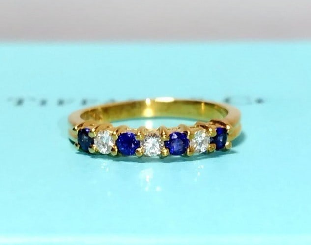 Tiffany Co 4 Sapphires 18k Yellow Gold Band Ring w/ Case: Tiffany Co 4 Sapphires 18k Yellow Gold Band Ring w/ Case Tiffany & Co's 18k yellow gold band ring showcases four stunning sapphires and three diamonds in a beautiful round shape. This vintage piece is