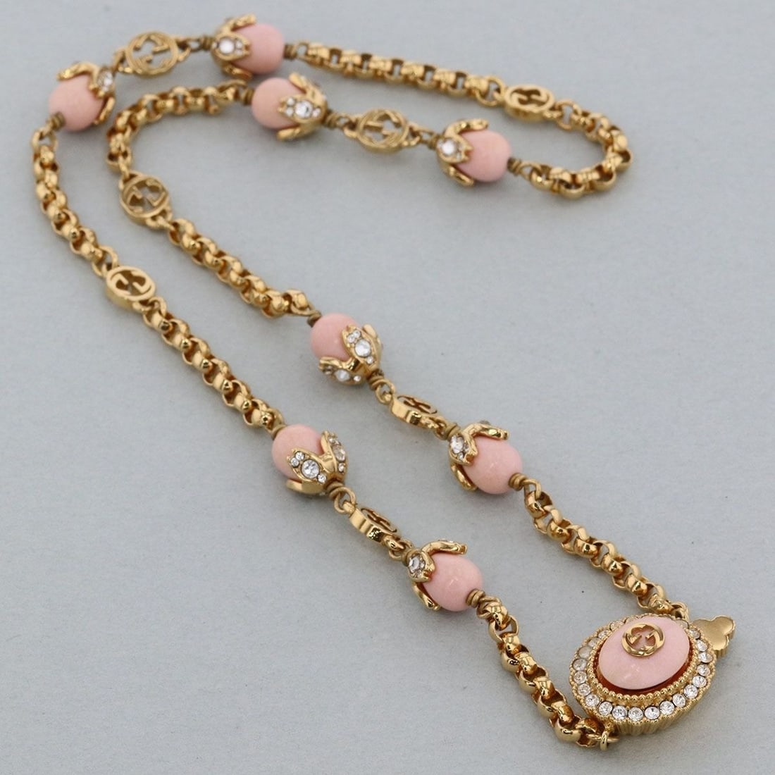 Gold tone necklace chain pink stone gucci rare interlocking g 17.3 inches: Gold tone necklace chain pink stone gucci rare interlocking g 17.3 inches Chain length: 17.3 inches, featuring a gold tone and pink stone design, with the iconic Gucci interlocking G logo. This neckla