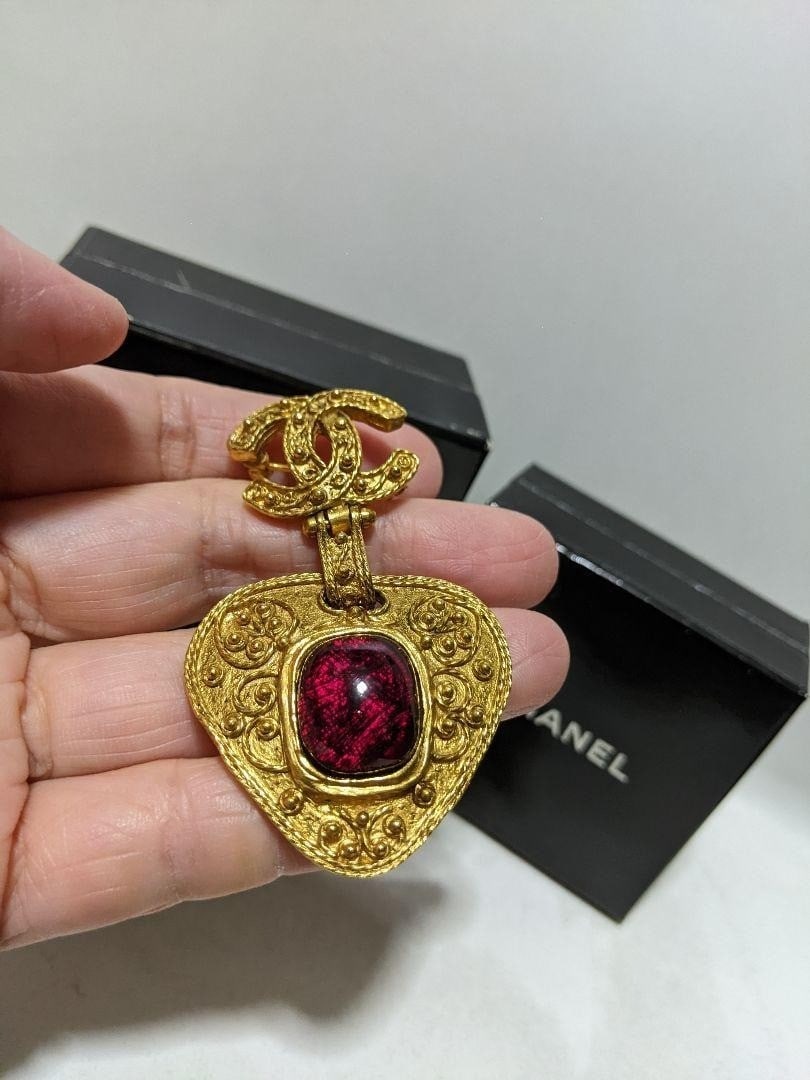 Vintage CHANEL Coco Mark CC Heart Red Gripoix Pin Brooch Gold tone: Vintage CHANEL Coco Mark CC Heart Red Gripoix Pin Brooch Gold tone Vintage CHANEL Coco Mark CC Heart Red Gripoix Pin Brooch Gold tone features a striking red Gripoix stone set against a gold-toned met