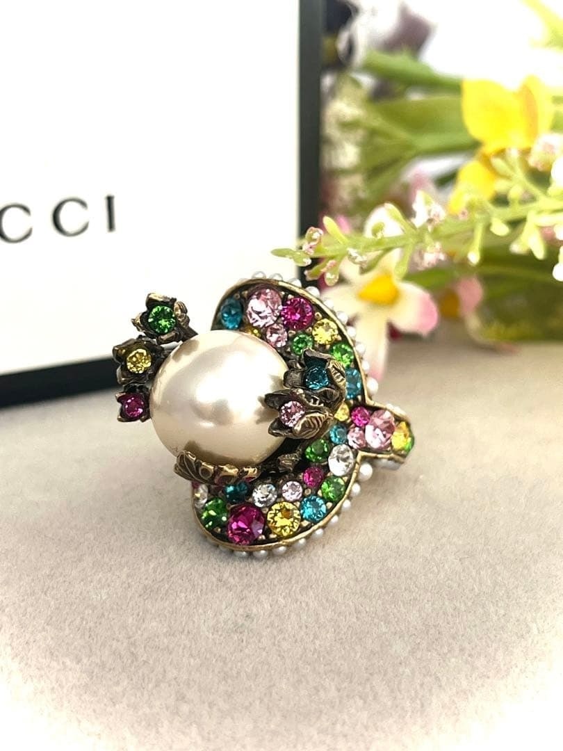 Gucci Faux Pearl and Clored Stone, Rhinestones Ring US5.5 with Original Box: Gucci Faux Pearl and Clored Stone, Rhinestones Ring US5.5 with Original Box Gucci's Faux Pearl and Clored Stone, Rhinestones Ring boasts a stunning multicolor white main stone surrounded by rhinestone