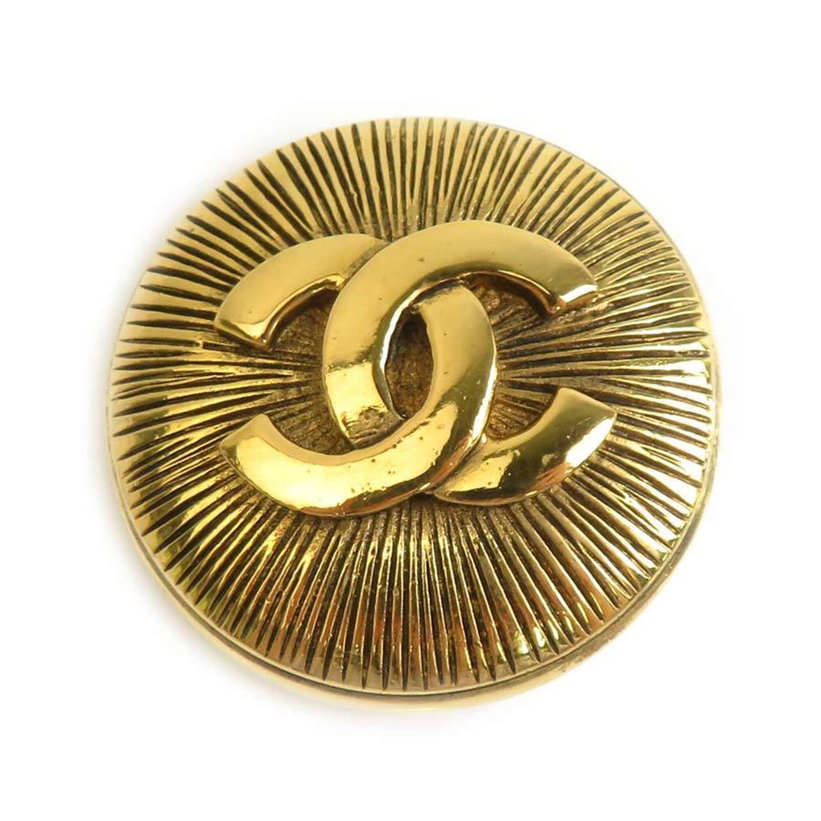 Metal brooch by Chanel: Metal brooch by Chanel This gold metal brooch by Chanel features a classic design with a subtle elegance. Measuring 3.5cm x 3.5cm, it bears the signature of the renowned fashion house on its surface.