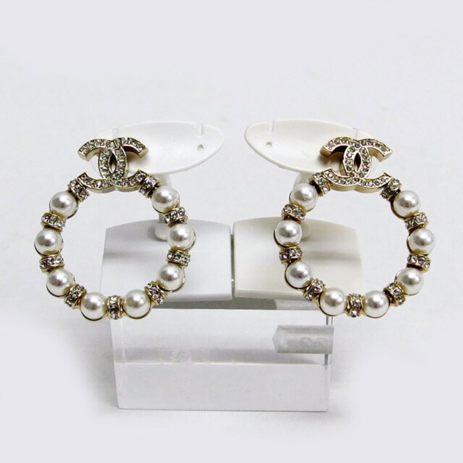 Earrings Metal Stud Chanel Rhinestone: Earrings Metal Stud Chanel Rhinestone Champagne gold, clear, and white rhinestones adorn these metal stud earrings in a classic Chanel design. The earrings are made from metal with a few traces of