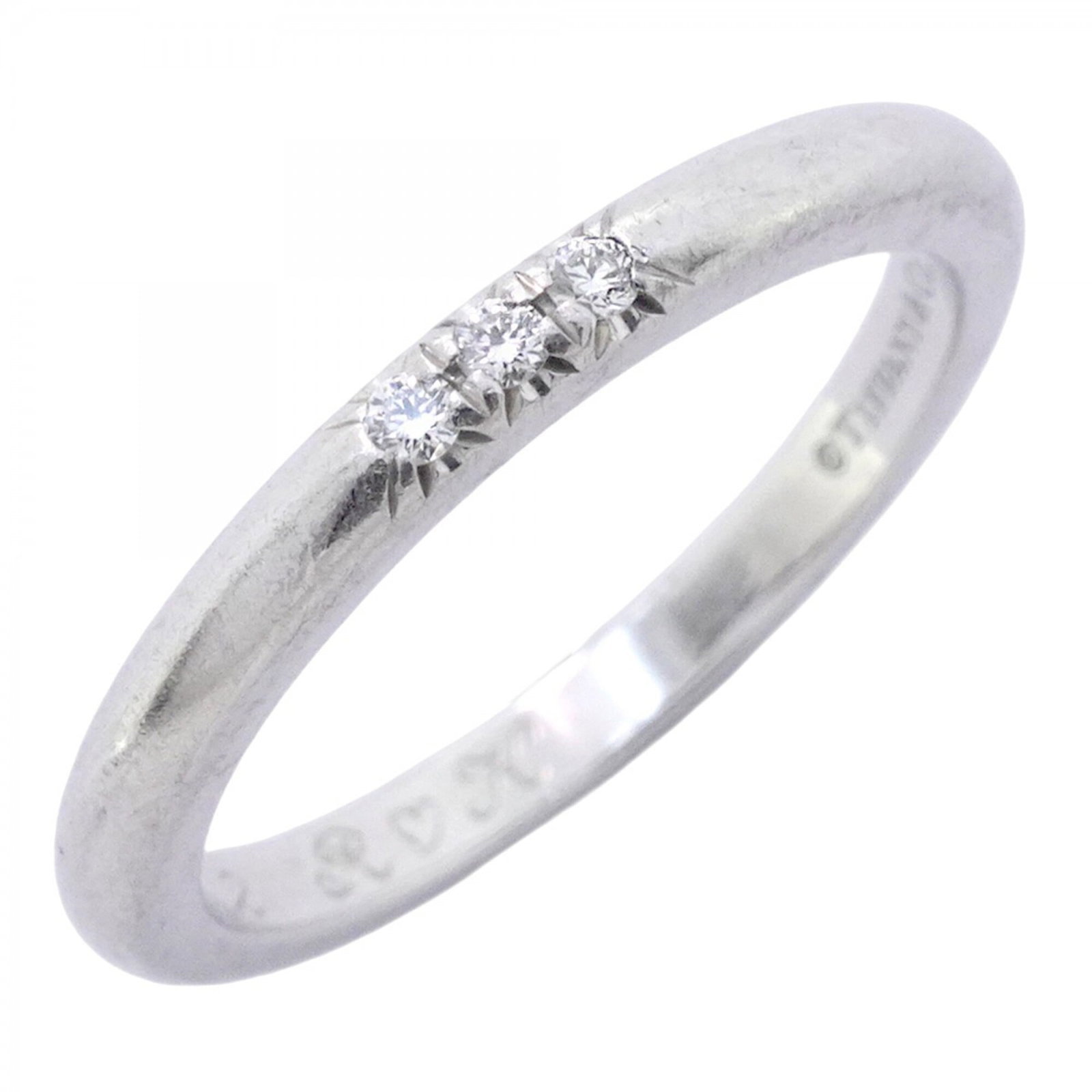 Platinum ring by Tiffany band: Platinum ring by Tiffany band Platinum ring by Tiffany features a diamond stone set in a band design. The item bears traces of usage and minor scratches, with some dirt visible but overall in good con