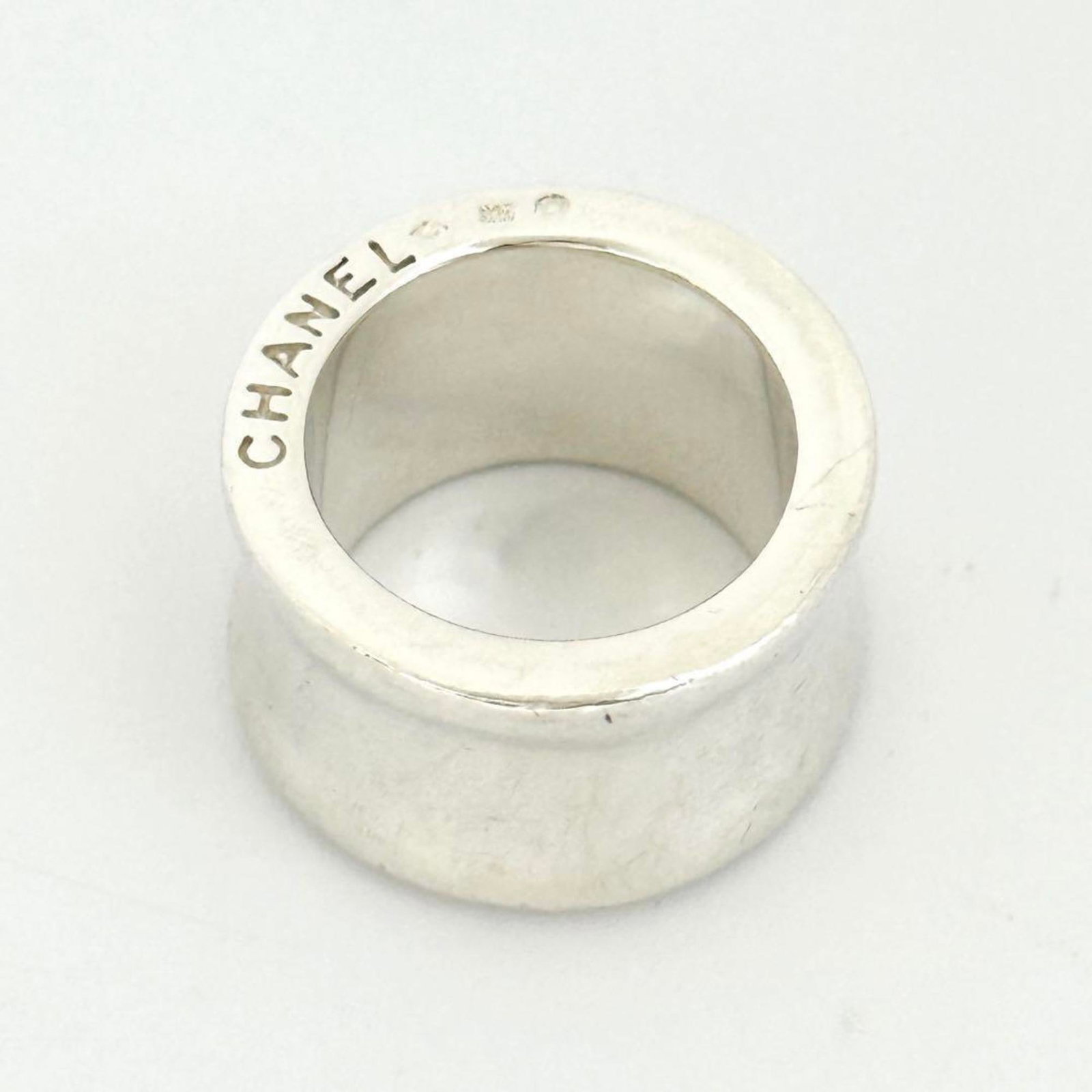 Silver band ring by Chanel: Silver band ring by Chanel Silver band ring by Chanel, featuring a sleek and sophisticated design in sterling silver (925). This used band ring shows signs of wear, with minor scratches and dirt