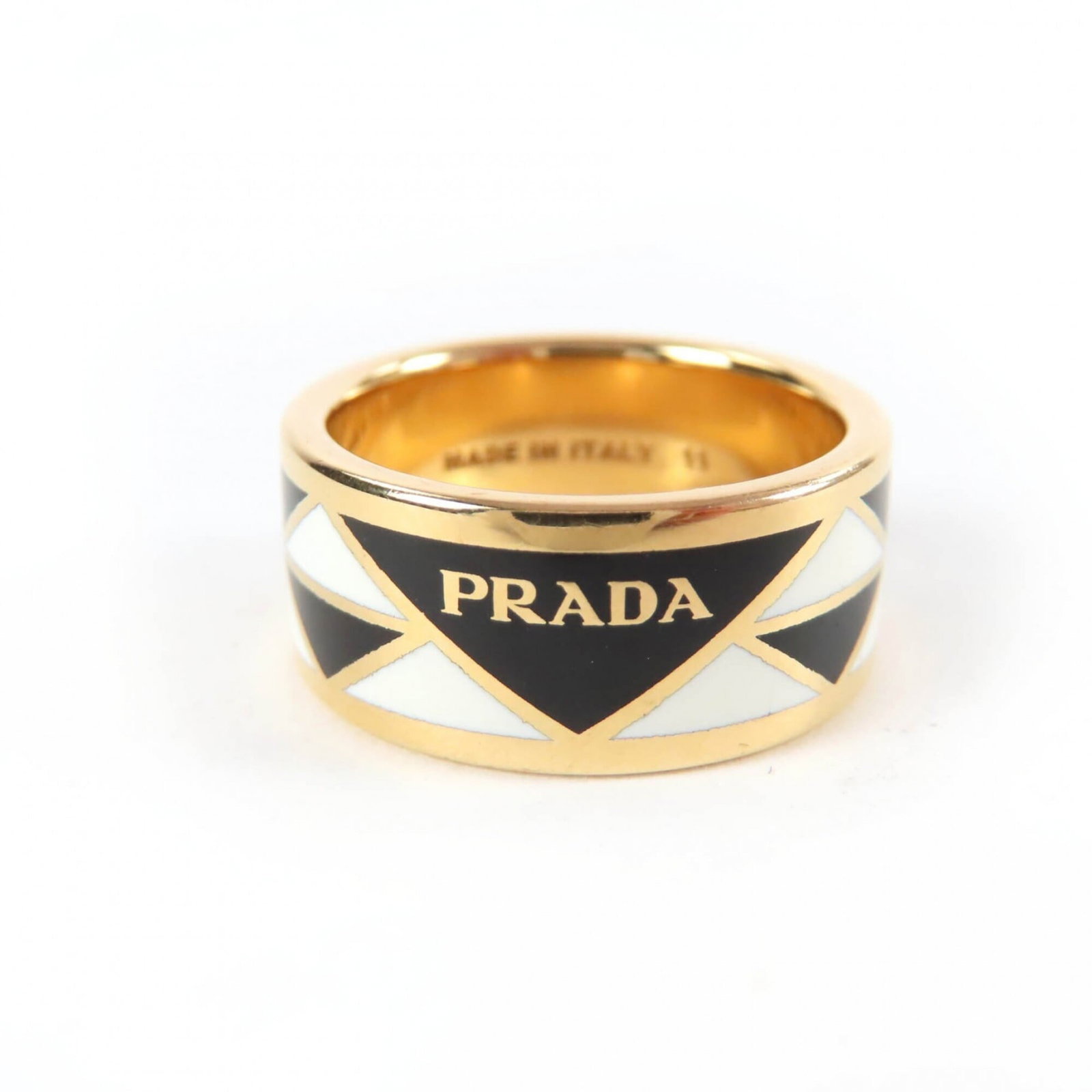 Ring by Prada: Ring by Prada The Prada band ring boasts sleek, modern design with a black finish. A small gold accent adds subtle sophistication to the overall look. Minor signs of wear are present on the exterior.