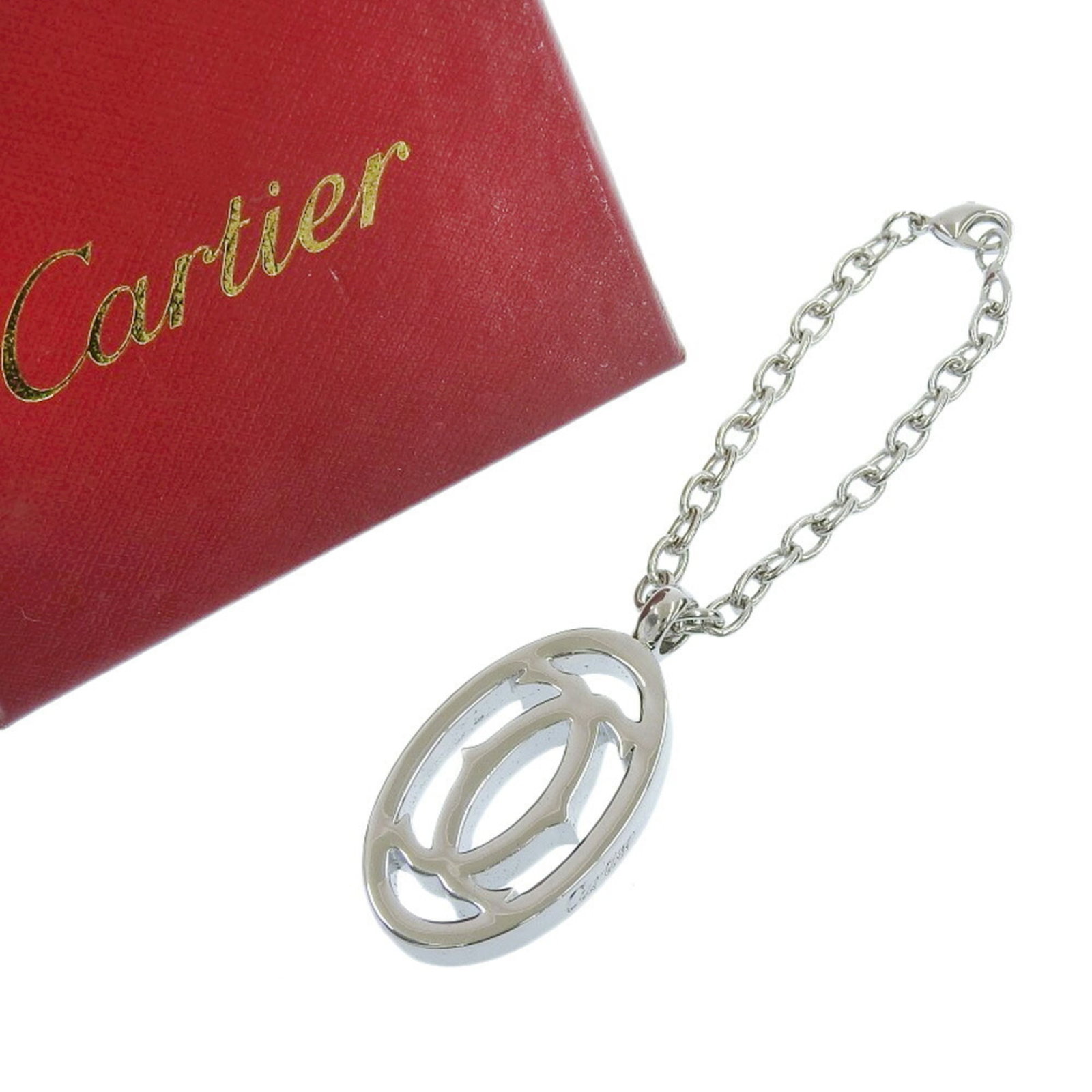 Keyring Metal Charm By Cartier: Keyring Metal Charm By Cartier Cartier metal charm keyring in silver, bearing a few traces of usage and minor scratches. The item remains in very good condition, with some signs of wear visible. A sma